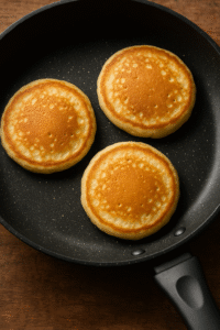 Cooking fluffy pancakes in a non-stick pan until golden brown.