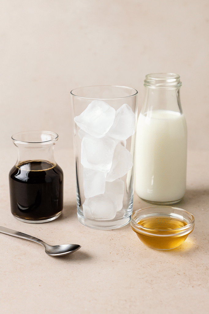 Iced coffee ingredients – chilled coffee, milk, ice cubes, and syrup on a wooden table.