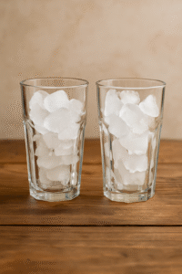 Two tall glasses filled with ice cubes for making iced coffee.