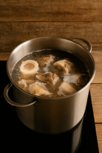 Beef bones simmering in a large pot of water for Romanian tripe soup, creating a rich beef broth.