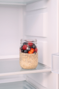 Jar of overnight oats with berries and chia placed in the refrigerator overnight.