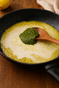 Butter, garlic, cream, Parmesan, and basil pesto blending together into a smooth sauce for Creamy Pesto Chicken Pasta.