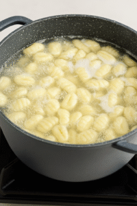 Boiling gnocchi in salted water until tender for Creamy Gnocchi with Spinach & Sun-Dried Tomatoes.