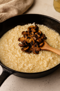 Mixing sautรฉed mushrooms back into creamy mushroom risotto for rich flavor. ๐