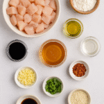 Honey Garlic Chicken ingredients – chicken, garlic, honey, soy sauce, vinegar, chili flakes, sesame seeds, and green onions prepared on a table.
