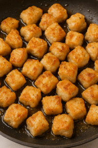 Golden fried chicken pieces sizzling in a skillet – Honey Garlic Chicken step 2.