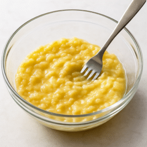 Banana Bread step 1 – ripe bananas mashed smoothly in a glass bowl with a fork.