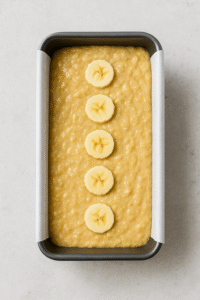 Banana Bread step 2 – banana bread batter poured into a loaf pan lined with parchment paper, ready to bake.