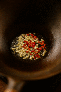 Sautéing garlic and red chili in a hot wok with oil for thai basil fried rice. 🌶️