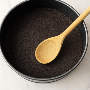 No-Bake Oreo Cheesecake step 1 – Oreo crumbs mixed with melted butter pressed into springform pan to form crust.