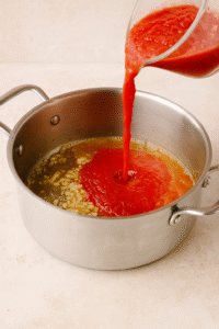 Adding tomatoes and vegetable broth to the pot