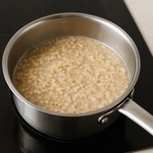Stirring rolled oats in a pot while cooking blueberry oatmeal until creamy texture forms.