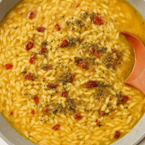 Orzo simmering in seasoned broth with herbs and sun-dried tomatoes for creamy Tuscan shrimp orzo.
