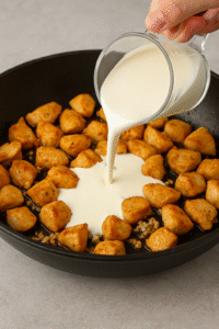 Heavy cream poured into the pan to create the sauce for creamy garlic parmesan chicken bites