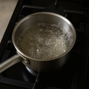 Boiling water in a saucepan on the stove to prepare peach iced tea.