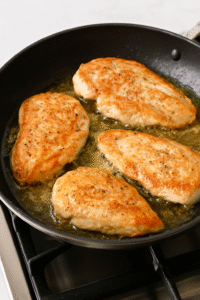 Chicken Marsala Recipe – searing seasoned chicken breasts in a skillet with olive oil and butter until golden brown.