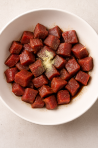 Diced raw steak cubes seasoned with soy sauce, garlic powder, salt, and pepper on a cutting board — Garlic Butter Steak Fried Rice prep.