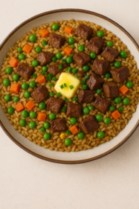Final plate of Garlic Butter Steak Fried Rice topped with steak cubes, peas, carrots, and a pat of melting butter with green onions.