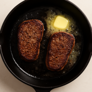 Steak Diane – beef steaks searing in butter in a hot cast iron skillet until golden brown