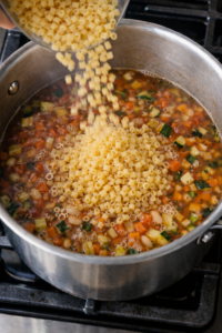 Adding pasta to Italian minestrone soup while cooking