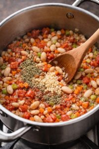 Adding diced tomatoes, cannellini beans, oregano, and thyme to pasta e fagioli soup