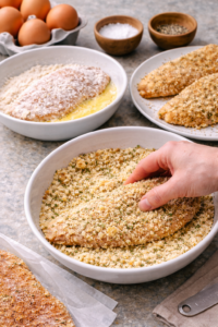 Coating chicken cutlets in Parmesan breadcrumbs to make crispy Parmesan chicken cutlets.