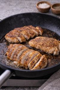 Searing seasoned chicken in a skillet until golden for miso chicken ramen.