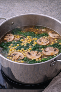 Adding mushrooms, spinach, and corn to miso chicken ramen broth.