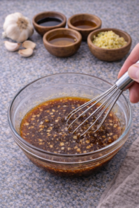 Whisking honey garlic sauce with soy sauce, garlic, and ginger for honey garlic salmon bites.