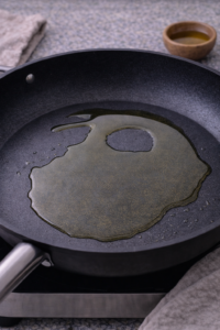 Heating olive oil in a skillet before cooking honey garlic salmon bites.
