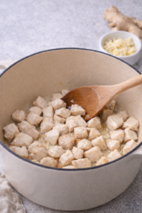 Chicken pieces lightly sautéed in a pot until just opaque.