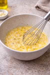 Eggs whisked with milk, salt, and pepper in a mixing bowl