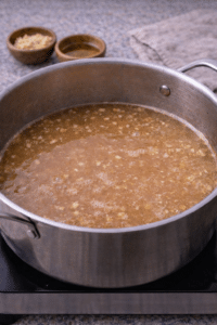 Simmering garlic and ginger broth for creamy sesame chicken ramen.