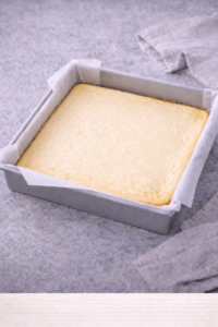 Baked cheesecake layer cooling in pan for strawberry cheesecake bars.