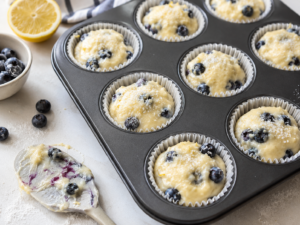 Blueberry lemon muffin batter divided into lined muffin cups and topped with coarse sugar